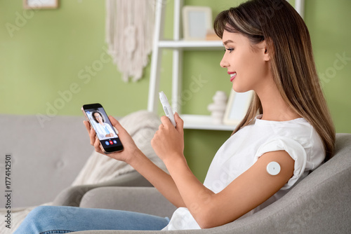 Diabetic young woman with glucose sensor and lancet pen receiving online cons...