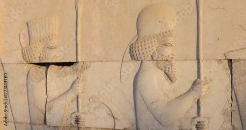 Close view of an Achaemenid stone relief at Persepolis: Persian guards in profile holding spears, curling beards and rosette motifs. Warm side light reveals ancient craftsmanship, ceremony, and empire