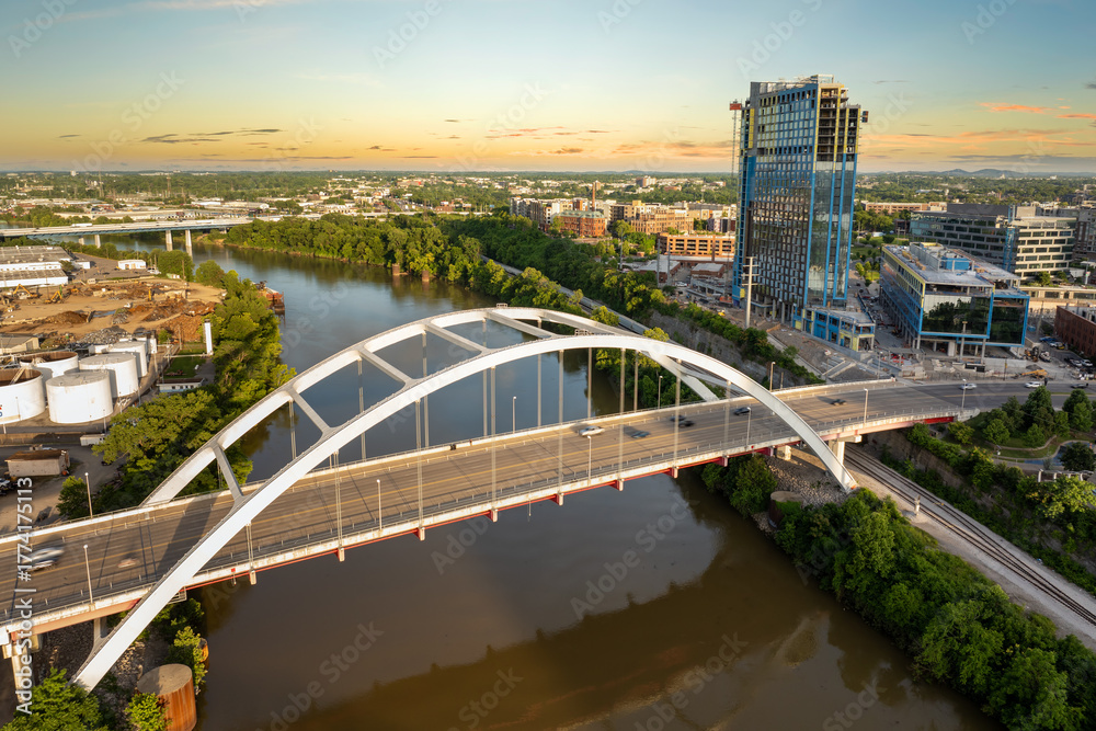 Obraz premium Downtown district highway bridge traffic in Nashville city, Tennessee at sunset. Brightly illuminated high skyscraper buildings in modern American midtown.
