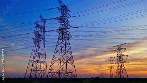 Silhouette of high voltage electricity transmission towers with power lines against a beautiful and colorful sunset sky