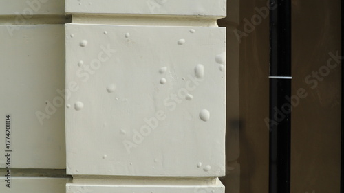 The white paint on the fence wall is bubbling due to the heat of the sun.