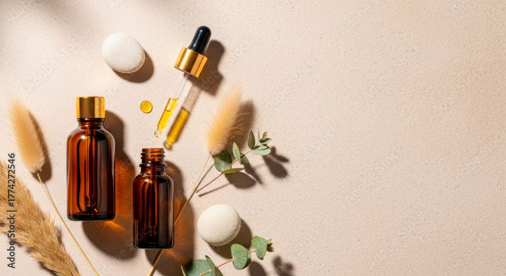 Obraz premium Glass bottles with essential oils and natural elements on beige background 