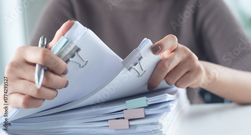 Businesswoman hands working with stack of paper document for searching and checking document on folder paper at busy work on desk office, close up