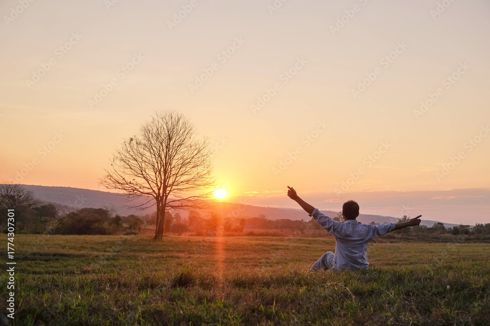 Fototapeta premium man and silhouette against the beautiful sunset sky over a summer field
