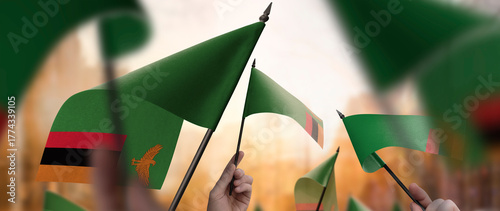 Zambia flags in their hands on a blurred urban background