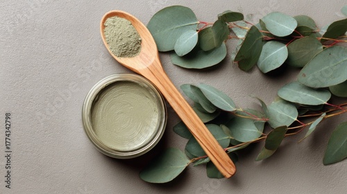 open jar of green clay mask surrounded by eucalyptus leaves and wooden spoon, matte texture, natural spa composition