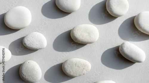 smooth white pebbles evenly spread on light gray surface, soft daylight, minimal spa composition background
