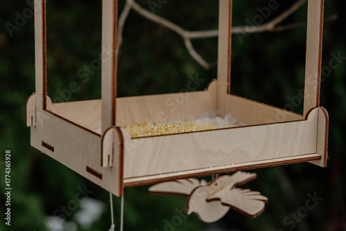 A wooden bird feeder filled with seeds hangs outside in winter