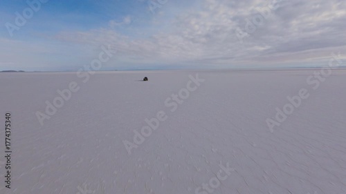 FPV drone shot chasing a 4x4 driving fast over the mirror-like surface of the Salar de Uyuni in Bolivia during a sunny day creating stunning reflections and a surreal sense of speed and freedom