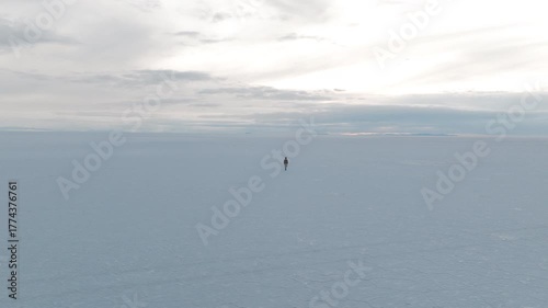 Aerial shot of a man walking alone through the endless white salt flats of Uyuni in Bolivia surrounded by silence and stunning natural beauty