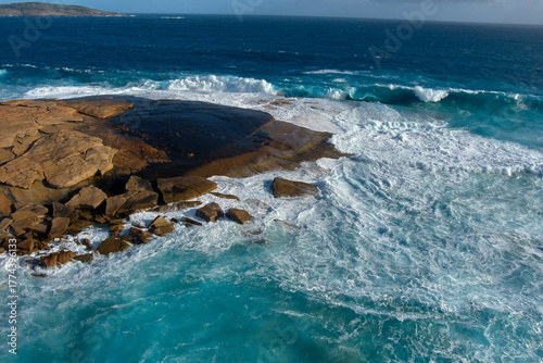 The wave receded as it crashed over the rocks, leaving a wash of white surf foam