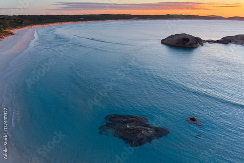 The morning sun paints the sky in orange hues as it rises over the distinct rocks at Twilight Beach, Esperance