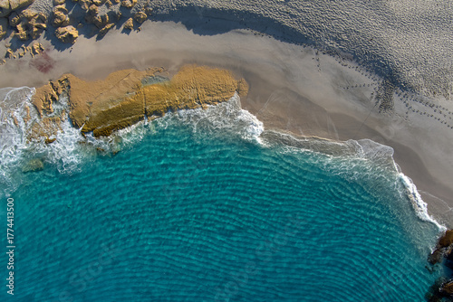 Waves ripple as they approach the shore and cascade onto the rocky outcrop