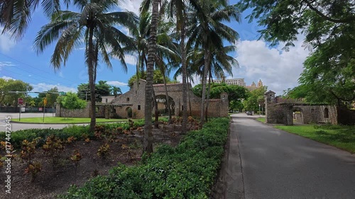 Historic stone entrance with palm trees and traffic in Miami

