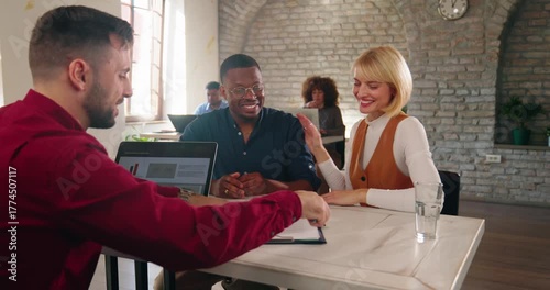 Happy multi-ethnic married couple, a Caucasian wife and an African American husband, sign a loan agreement with a bank officer in a modern banking office.