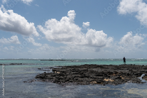 Mann steht auf einem Felsen und angelt am Meer in Mauritius