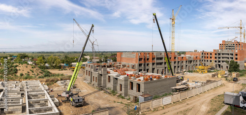 Panorama of a residential complex construction site with cranes and equipment
