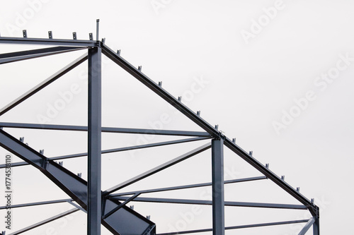 Metal construction, in the photo the structure of the building frame made of metal beams against the background of a gray sky