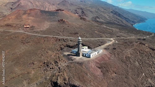 Wide aerial drone circling shot around the Faro de Orchilla Lighthouse situated on the dramatic volcanic coast of Punta Orchilla, El Hierro, Canary Islands, Spain.