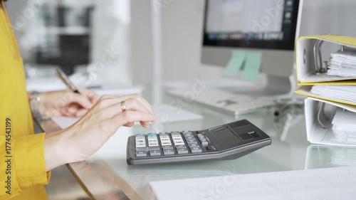 Woman in yellow blouse calculating finances, managing budget, doing taxes, working on accounting documents in office workspace. Audit and taxes in business