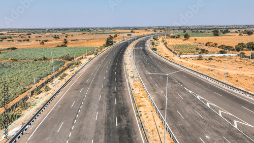 Modern highway curving through dry agricultural landscape showcasing India’s growing transportation network, smart road planning, and advanced infrastructure development.