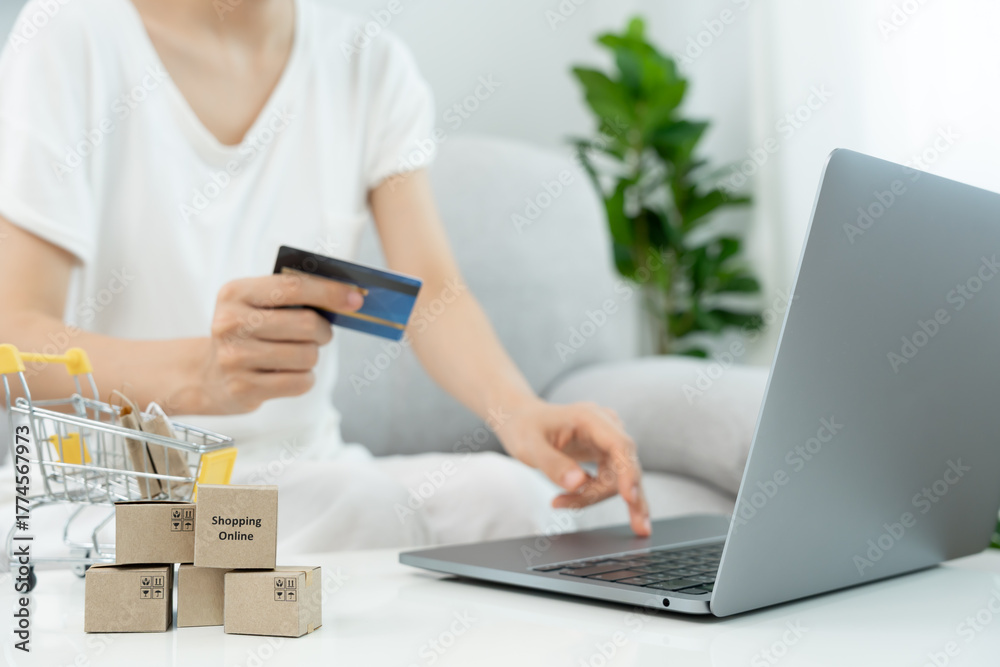 Fototapeta premium woman using laptop for online shopping at home. Hand holding mobile phone with payment detail page display and credit card, stay home, technology, electronic commerce, internet, market place
