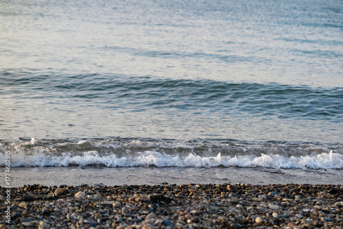 Wave in white foam on a pebble beach. Sea landscape.
