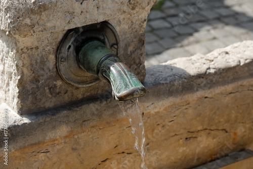 This stone fountain, found in Geneva, Switzerland, has a metal spout from which water flows