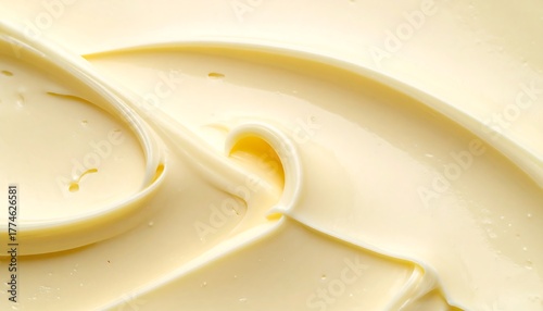 Macro shot of creamy, swirled, yellow food product, smooth and glossy with highlights and shadows creating depth
