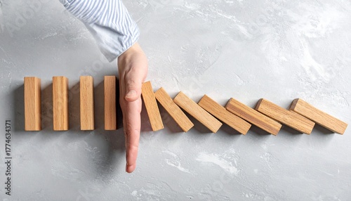A hand preventing the domino effect concept of risk management and strategy planning