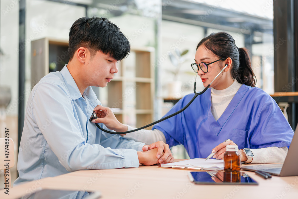 Fototapeta premium Young patient and nurse in clinic using stethoscope during checkup, calm supportive scene