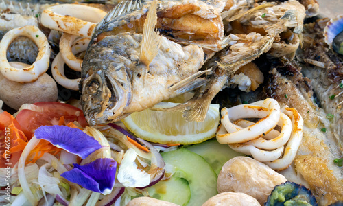 A grilled fish mix plate with various types of fish, seafood, scallops and squid rings.