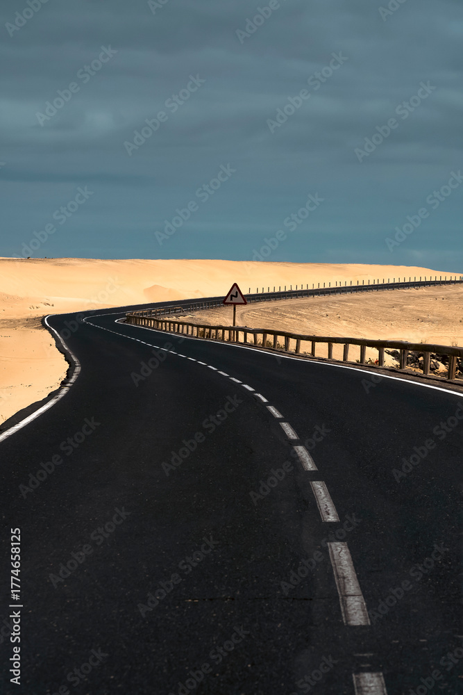 Fototapeta premium An asphalt road among desert with sandy dunes.