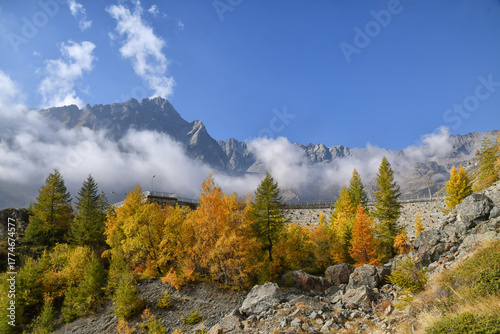 Paesaggio autunnale montano con foreste colorate e alte vette tra le nuvole