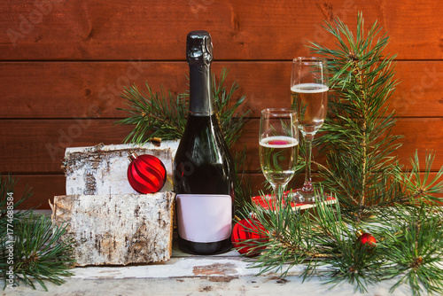 Bottle of champagne, glasses of champagne, balls, pine branches,  and pile of firewood.