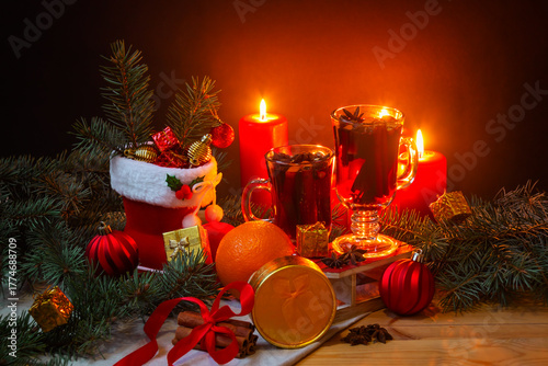 Glasses of mulled wine, burning candles, christmas stocking, christmas balls, pine branches, gifts and balls on wooden table. Christmas concept.
