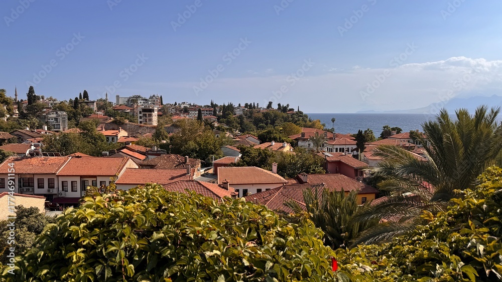 Naklejka premium Panoramic view of Kaleici old town in Antalya featuring traditional houses with characteristic terracotta tile roofs overlooking the bright Mediterranean Sea