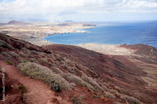 Discovering Tenerife: unforgettable view of pretty coastal town, deep blue water surface of Atlantic Ocean and cloudy sky