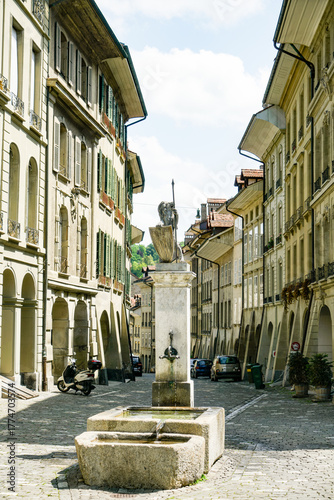 Fototapeta Naklejka Na Ścianę i Meble -  A small fountain is in the middle of a narrow street in Bern Switzerland