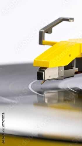 Close-up of a vintage record player turntable with yellow arm and gray platter