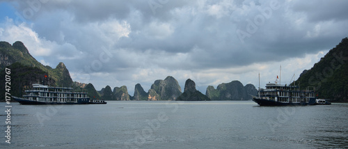 Cruise boats sailing past limestone karsts in Ha Long Bay Vietnam