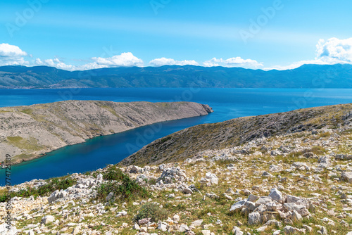 Scenic coastal view of rocky peninsula and blue sea under clear sky. Vela Luka beach, Krk island, Croatia