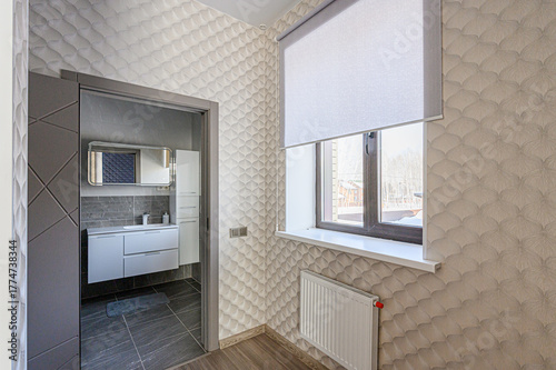 room featuring patterned wallpaper, a window with a roller blind, and a view into a modern bathroom