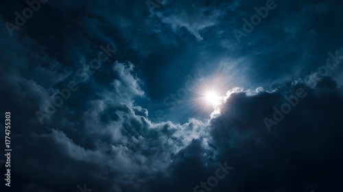 Sunlight streams dramatically through dark moody clouds against a deep blue sky