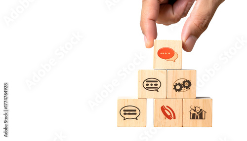 Hand placing a communication icon cube atop a pyramid of similar wooden blocks on black