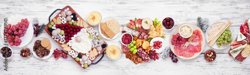 Christmas holiday charcuterie table scene on a white wood banner background. Above view. Assorted cheese, fruit and meat appetizers.