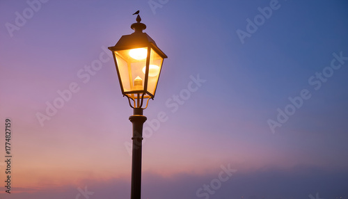 Illuminated Streetlight Against a Twilight Sky with Gradient of Purple to Blue and Golden Light Emitting from the Lantern at Dusk