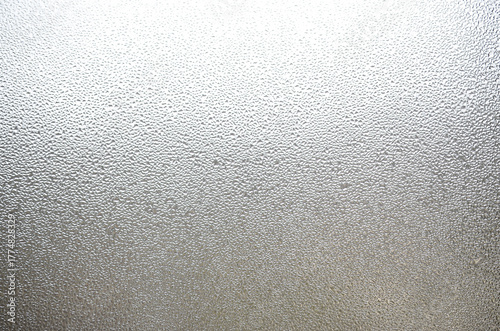 A photo of the glass surface of the window, covered with a multitude of droplets of various sizes. Background texture of a dense layer of condensate on glass
