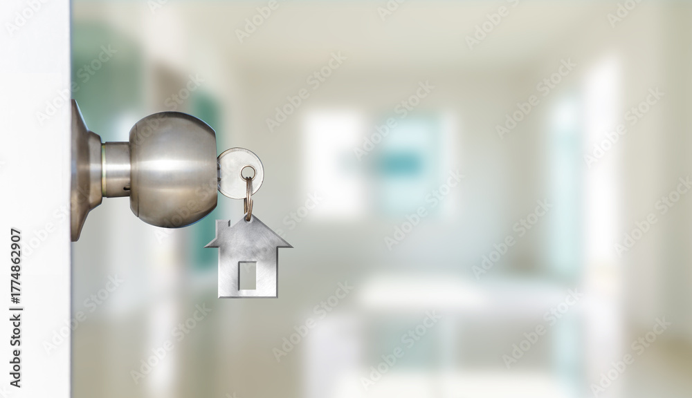 Fototapeta premium Key with house-shaped keychain in doorknob, symbolizing home access, ownership, security, or real estate.