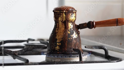 Male Hand Holding Traditional Coffee Turk with Overflowing Coffee on Stove Flame